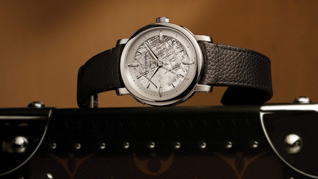 ESFERAS TEXTURIZADAS La nueva textura de la esfera, apreciable especialmente en los modelos de oro rosa, es una referencia directa a la superficie granulada del Monogram de Louis Vuitton. Se desarrollaron y perfeccionaron sellos de esfera a lo largo de varios ensayos para conseguir transmitir la flexibilidad y el tacto del lienzo en una esfera de metal.